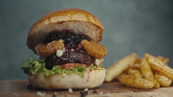 Grote Burger met rundvlees, tomaten, champignons en komkommers met gesmolten kaas op een houten plank — Stockvideo