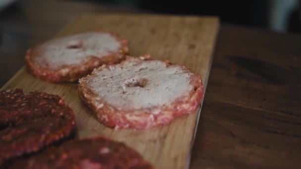 Húspogácsát készítenek elő egy Grillezőre. A szakács megfűszerezi a hamburgert a friss húsból. — Stock videók