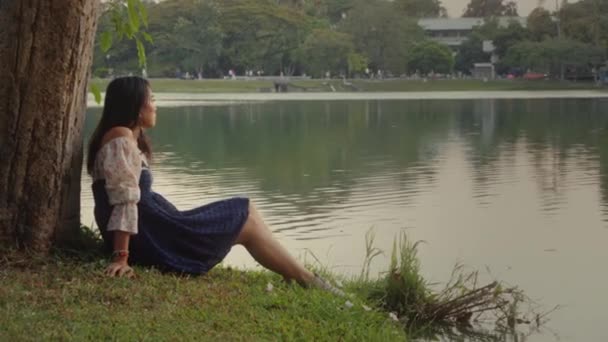 Transgender asijské žena opírající se o strom v parku těší okamžik. — Stock video