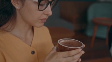 Woman is enjoying her cup of coffee sitting at coffee shop.