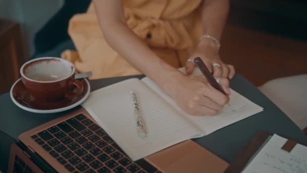 Dívka píše do zápisníku v kavárně. — Stock video