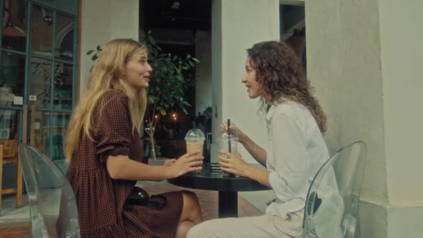 Two women sit in a coffee shop on the street and discuss — Vídeo de Stock