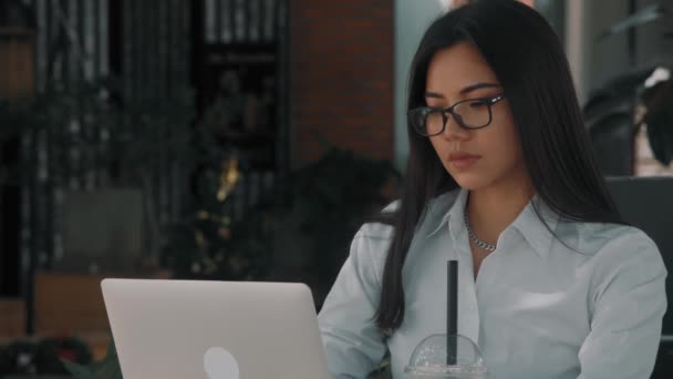 Asiatique attrayant jeune femme portant des lunettes, travaillant à son ordinateur portable dans un café terrasse extérieure — Video