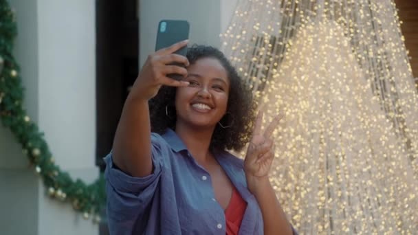 Beautiful, fashionable African-American woman taking selfies in the street against the Christmas tree — Stock Video