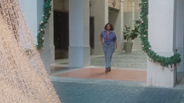 Beautiful, fashionable African-American woman walking down the street in front of Christmas decorations — Stock Video