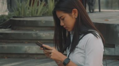 Gözlüklü Asyalı çekici genç kadın, sokakta telefon kullanıyor..