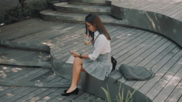 Aziatisch aantrekkelijk jong vrouw met bril, maakt gebruik van telefoon op de straat. — Stockvideo