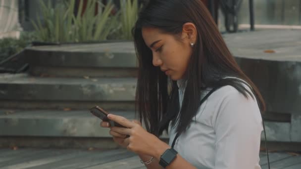 Aziatisch aantrekkelijk jong vrouw met bril, maakt gebruik van telefoon op de straat. — Stockvideo