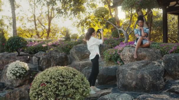 Una hermosa modelo negra posa para un fotógrafo. Sesión de fotos de moda con estilo en un jardín de cactus — Vídeos de Stock