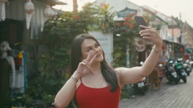 Güzel bir trans kadın sokakta yürürken selfie çekiyor.