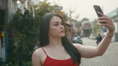 Güzel bir trans kadın sokakta yürürken selfie çekiyor.