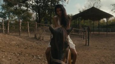 Genç kadın ata biniyor.