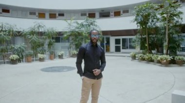 Genç Afrikalı Amerikalı iş adamı şirket binasının önünde duruyor.