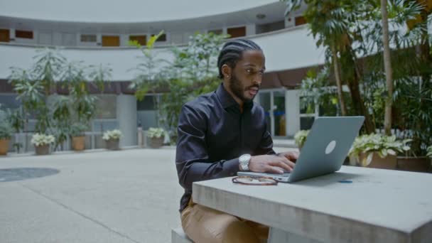 Young African-American businessman working with a laptop on the street — Stock Video