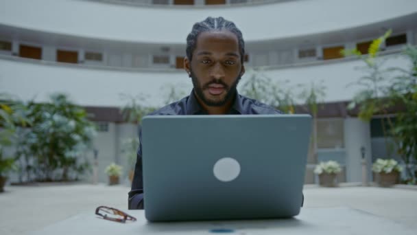 Jonge Afro-Amerikaanse zakenman werkt met een laptop op straat — Stockvideo