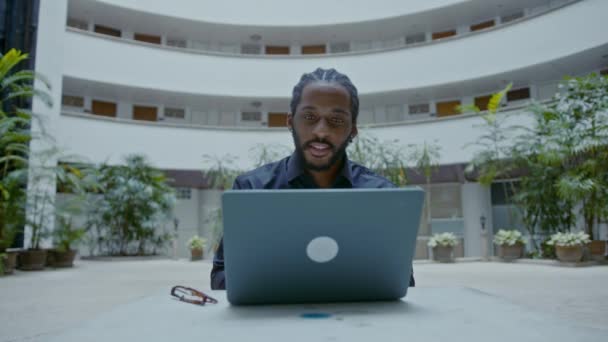 Молодой афроамериканский бизнесмен, работающий с ноутбуком на улице — стоковое видео