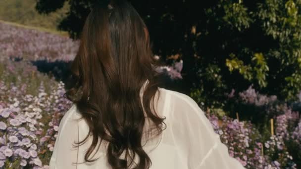 Young asian woman walks in flower field on sunset — Vídeos de Stock