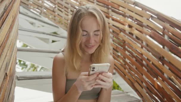 A pretty young woman with vitiligo pigmentation sits on the stairs, chatting on the phone — Wideo stockowe