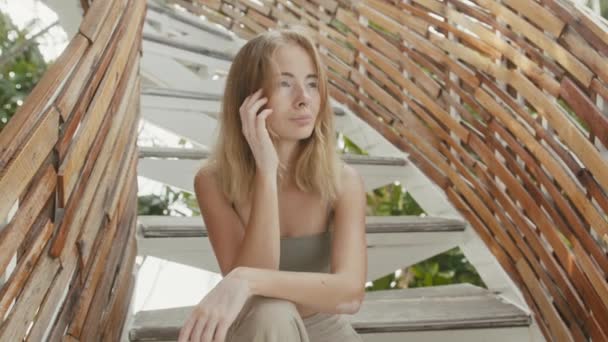 Красива молода жінка з пігментацією вітіліго сидить на сходах, дивлячись на камеру — стокове відео