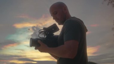 Kameralı bir kameraman güzel bir gün batımı çekiyor.