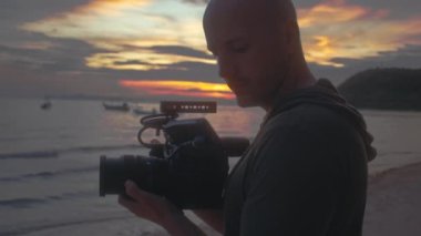 Kameralı bir kameraman güzel bir gün batımı çekiyor.