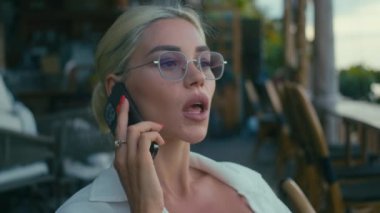 Sarışın kadın bir kafede telefonla konuşurken konuşuyor.