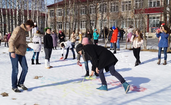 Young people draw colour water on snow on holiday of the shrovet — Stock Photo, Image