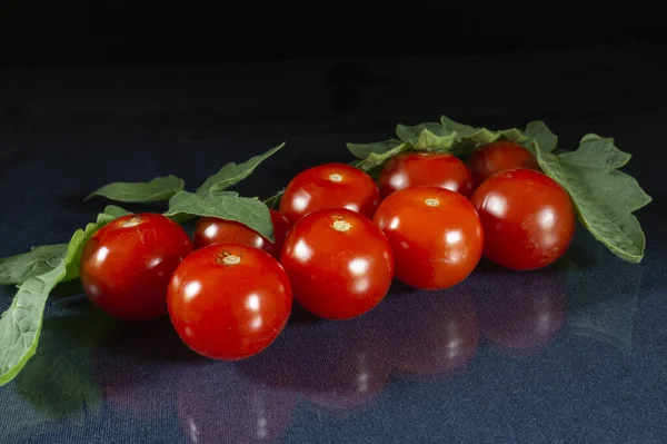 緑の葉でテーブルの上にトマトを熟す 黒を背景にした食べ物 — ストック写真