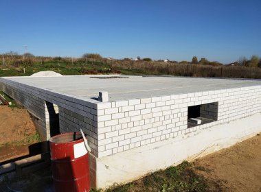 Kırsalda beyaz tuğlalı bir evin temeli. Mavi gökyüzü arka planında inşaat alanı