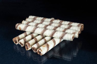 Masanın üzerinde yansıması olan tatlı çubuklar. Siyah arkaplanda çay için tatlı