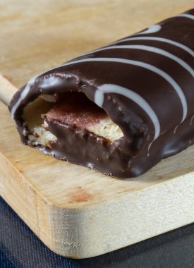 Mutfaktaki ahşap bir tahtanın üzerinde tatlı bir rulo. Gıda ürünleri siyah arka planda