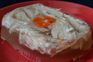 Aspic chicken meat on a red plate. Festive delicacy on the table