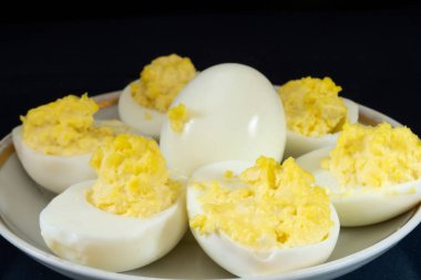 Beyaz tabakta mayonez ile doldurulmuş yumurta sarısı. Siyah arkaplanda yemek