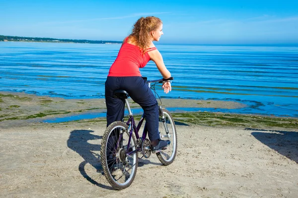 Schöne Frau mit Fahrrad am Meer — Stockfoto