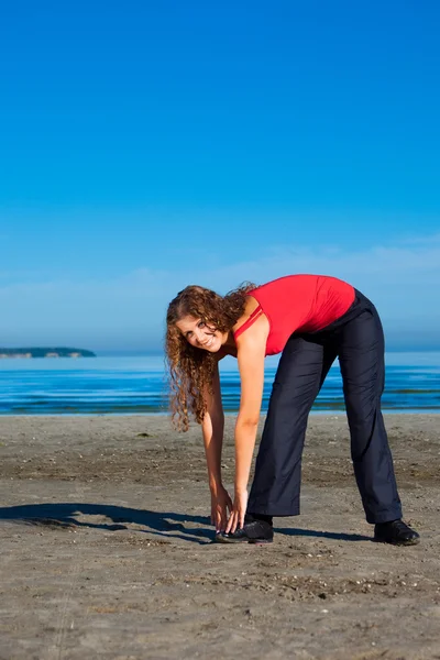 Κορίτσι κάνει ασκήσεις πρωί στην παραλία — Stock fotografie