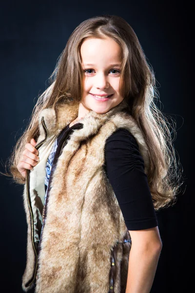 Girl with fair long hair in fur vest on dark background — Stock Photo, Image