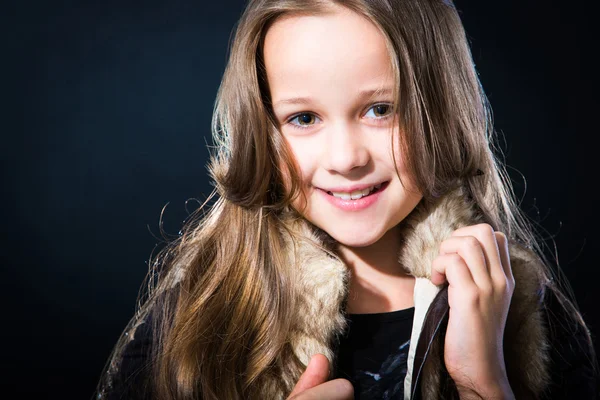 Menina com cabelo longo claro em colete de pele no fundo escuro — Fotografia de Stock