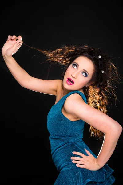 Menina bonita em vestido turquesa brincando com o cabelo no preto — Fotografia de Stock