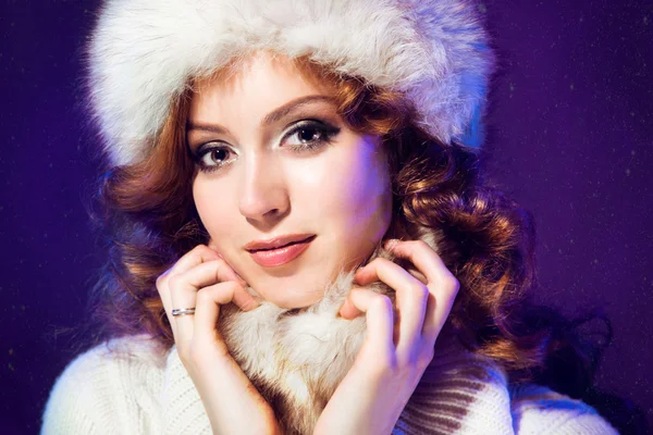 Beautiful girl with winter fur cap on purple — Stock Photo, Image