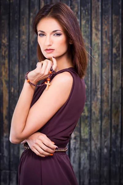 Beautiful girl with christian beads against old wooden wall — Stock Photo, Image