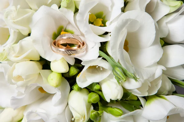 Wedding rings on beautiful bouquet of white freesias — Stock Photo, Image