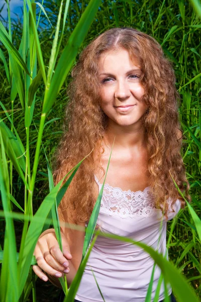 Hermosa chica en rosa entre la hierba verde alta del prado de verano —  Fotos de Stock