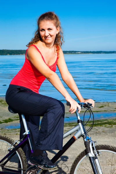 Vacker kvinna med cykel på havet — Stockfoto