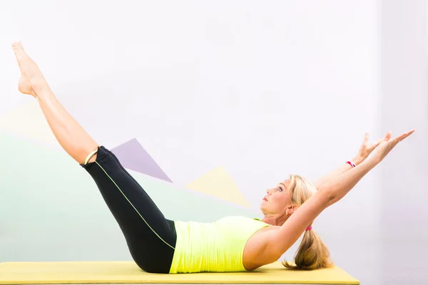 Schöne Pilateslehrerin mit gelber Yogamatte — Stockfoto