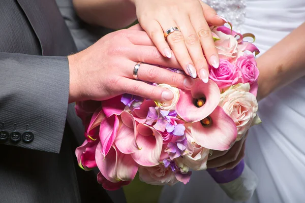 Hands of bride and groom on beautiful wedding bouquet — Stock Photo, Image