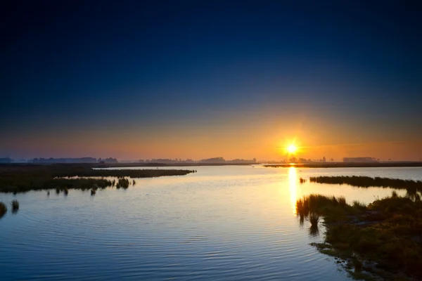 Sun rising up over blue lake — Stock Photo, Image