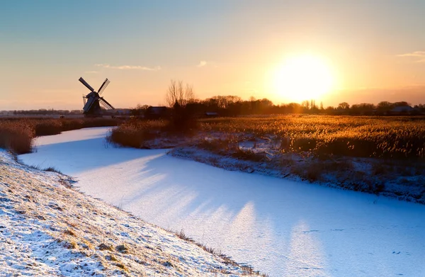 Salida del sol sobre molino de viento holandés y canal congelado —  Fotos de Stock