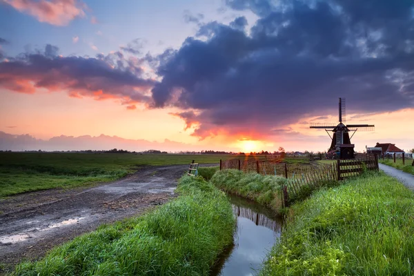 Warmer Sonnenaufgang über holländischer Windmühle und Fluss — Stockfoto