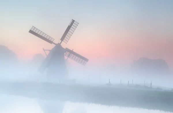 Windmill in dense fog at summer sunrise — Zdjęcie stockowe