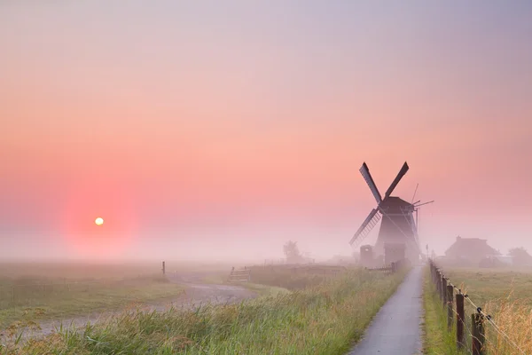 Windmill and rising sun in fog — Stock Photo, Image